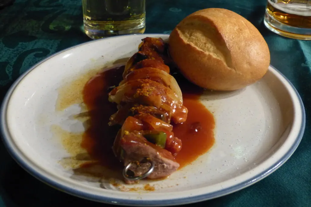 Schaschlikspieß mit Sauce auf dem Teller bestreut mit Curry und Paprikapulver.