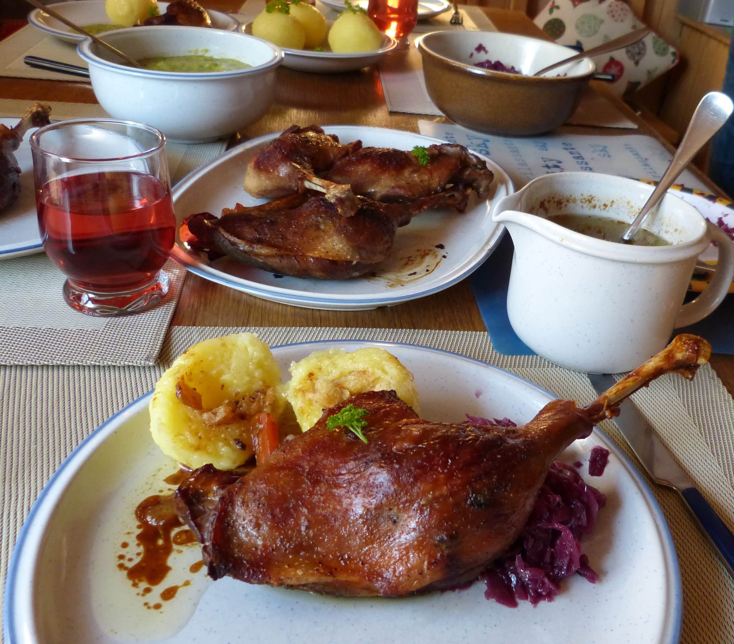 Sunday lunch in Bavaria: Beautifully golden brown German roasted goose legs and gravy served with  potato dumplings, savoy cabbage (Wirsing), and blaukraut.