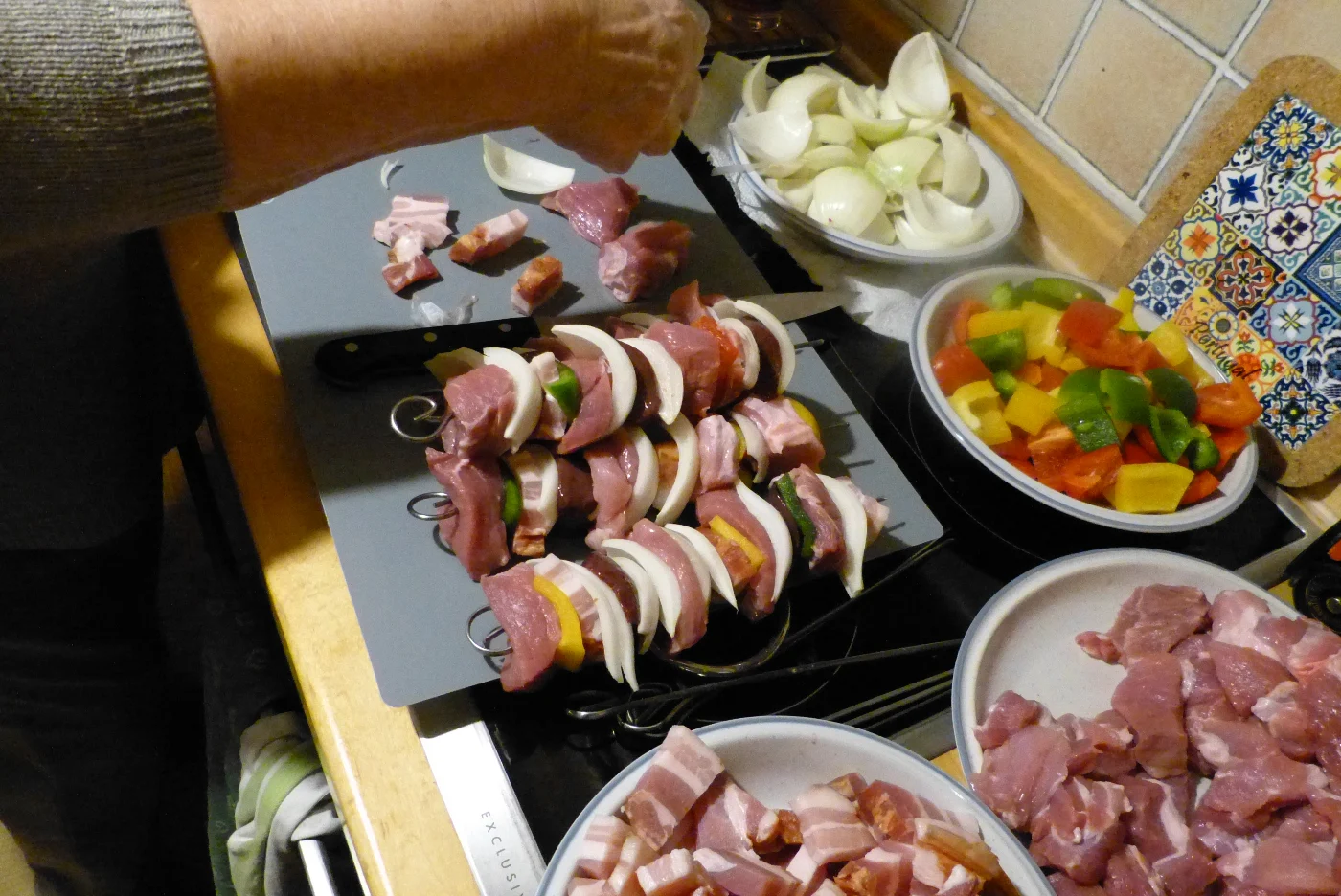 Das Fleisch und das Gemüse abwechselnd auf Spieße stecken, um Schaschlikspieße herzustellen.