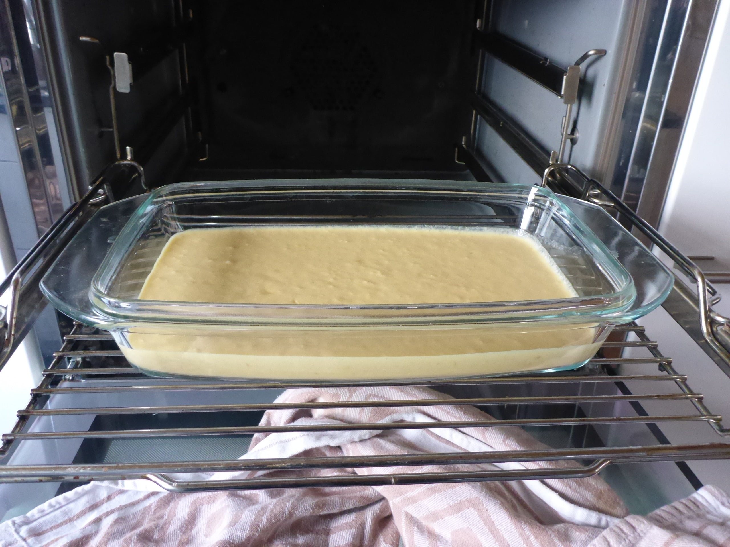 Malva Pudding Rührteig, der in einer Glasform bereitsteht, kurz bevor er gebacken wird.