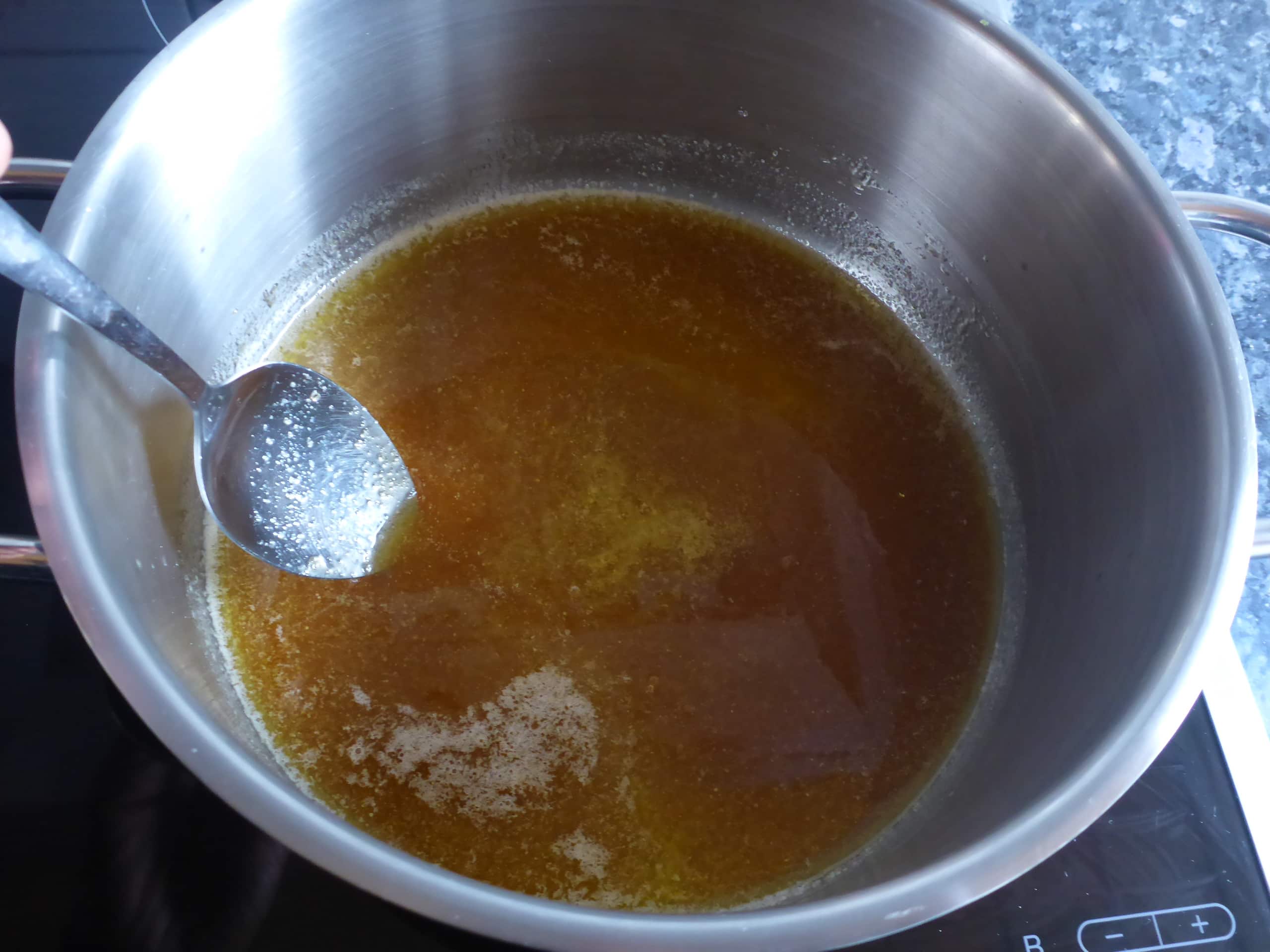Ein Bild, das den Prozess der Zubereitung des Malva Pudding Sirups ohne Sahne zeigt, mit Zucker, Wasser, und Butter, die miteinander vermischt werden.