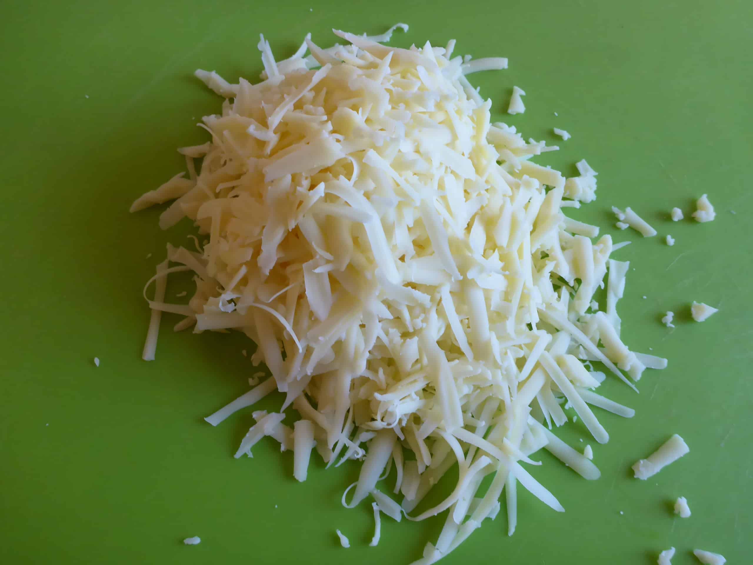 Freshly grated cheese on a cutting board.