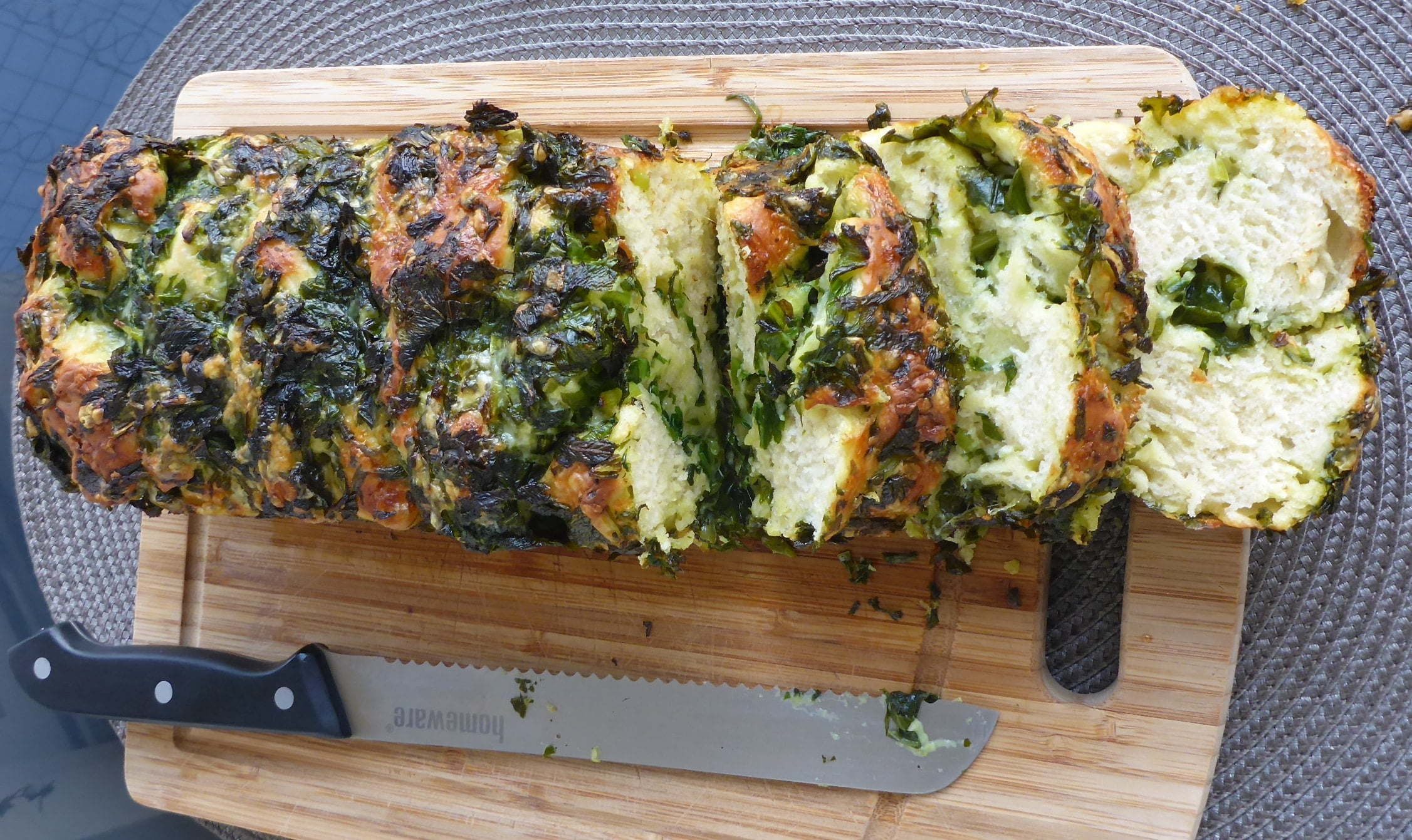 Freshly Baked Wild Garlic Bread on a Wooden Cutting Board, Sliced and Ready to Savor.
