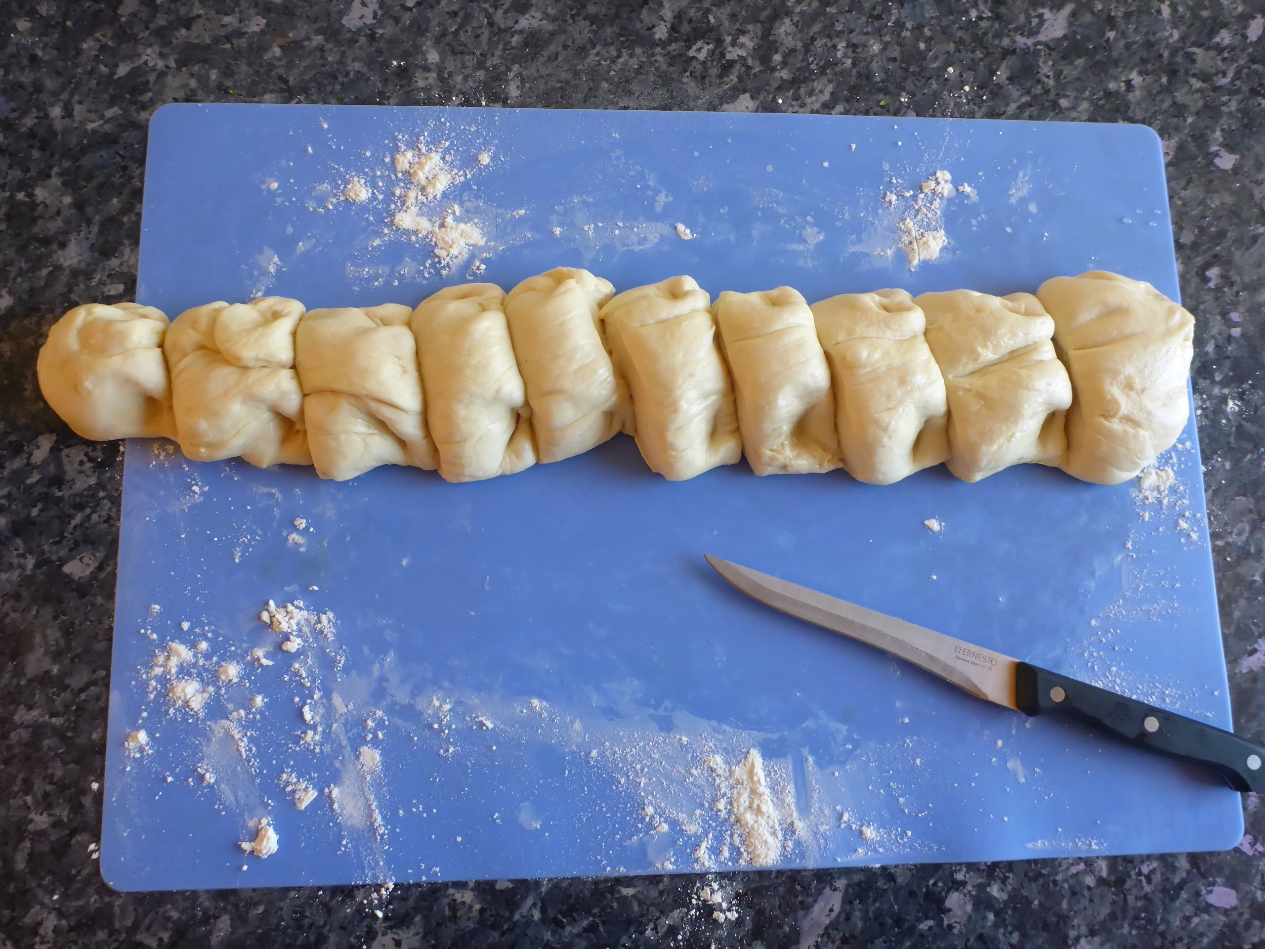 Yeast dough long loaf on a cutting board cut into rolls.