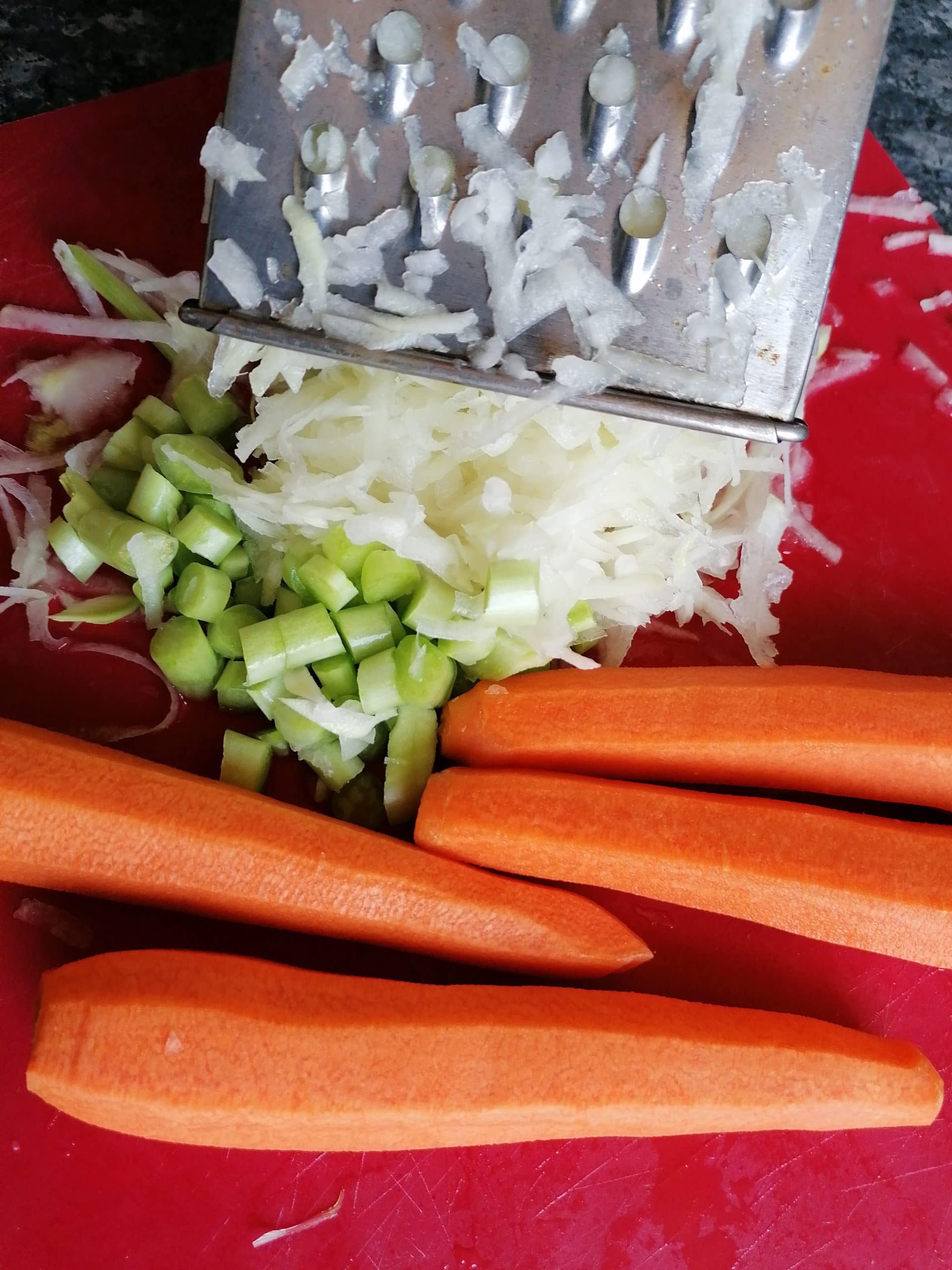 An image capturing the preparation process of Kohlrabi Quiche, showcasing a peeled kohlrabi being grated on a box grater. The grater's sharp blades transform the kohlrabi into fine shreds, ready to be incorporated into the quiche filling.