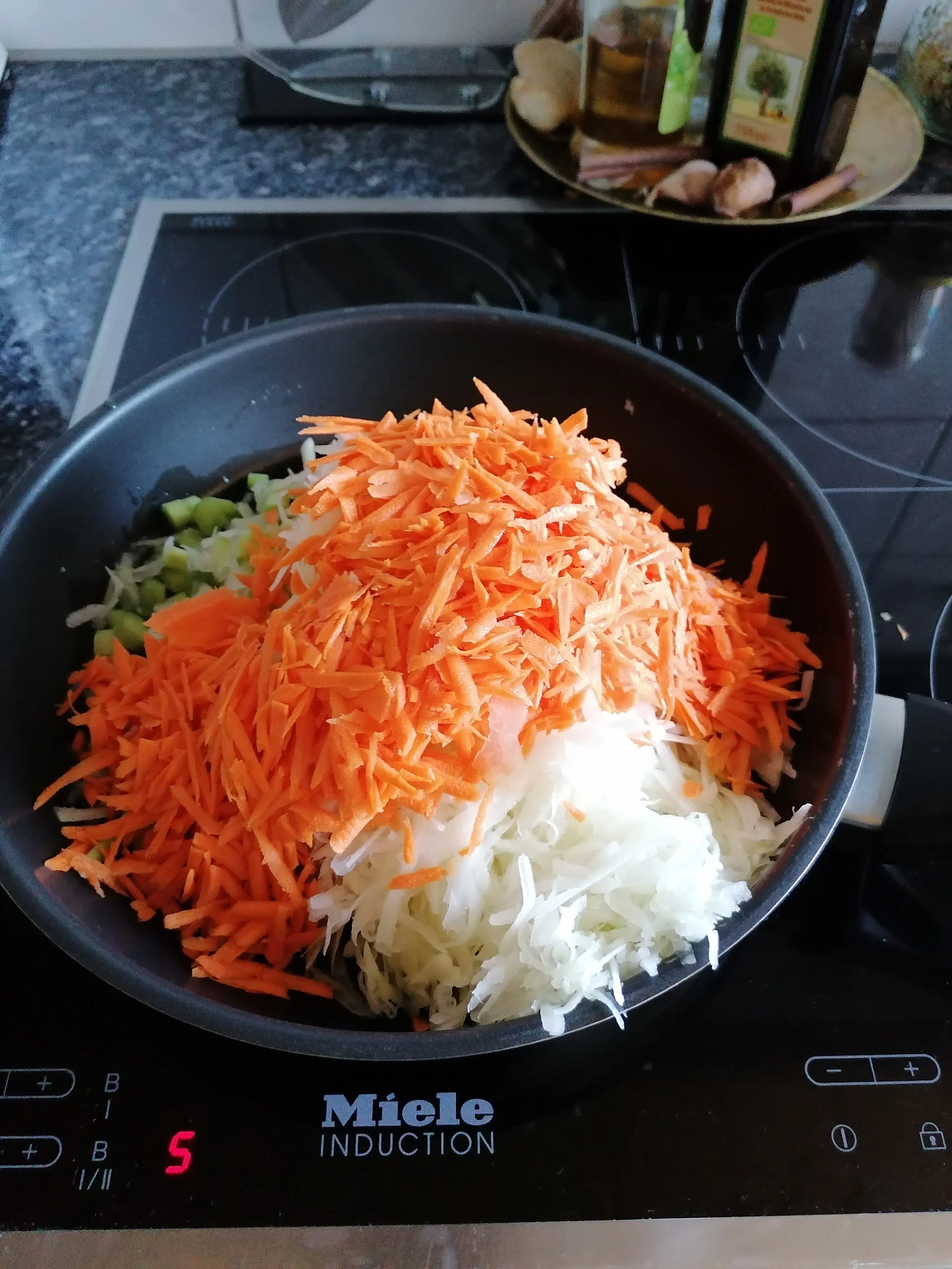A captivating photo displaying the vivid colors of grated kohlrabi and grated carrots sizzling in a pan on a stove. The vibrant green and white shreds of kohlrabi harmoniously blend with the rich orange hues of the carrots, creating a visually enticing and nutritious mixture ready to be used in a delectable culinary masterpiece.