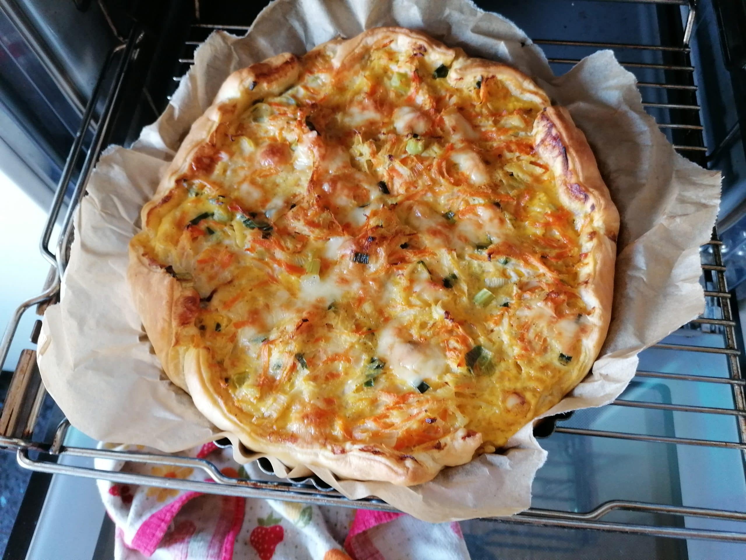 Freshly baked Kohlrabi Quiche, golden-brown and beautifully risen. The buttery, flaky puff pastry crust cradles the creamy and flavorful filling, adorned with specks of grated kohlrabi, carrots, and sliced spring onions. 