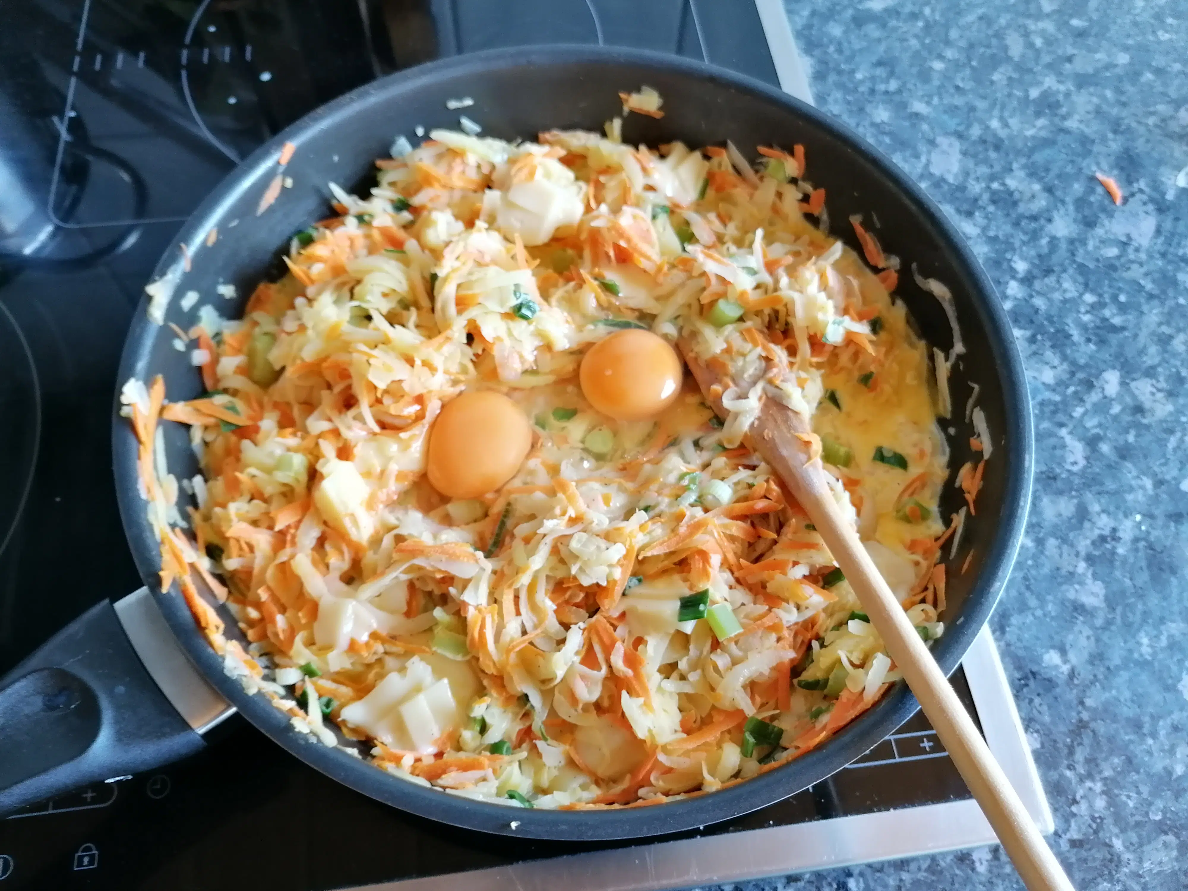 Cheesy and creamy sauce for kohlrabi quiche in the making. Eggs are added to the pan with whipped cream, cheese, kohlrabi, spring onions and carrots mixture. 