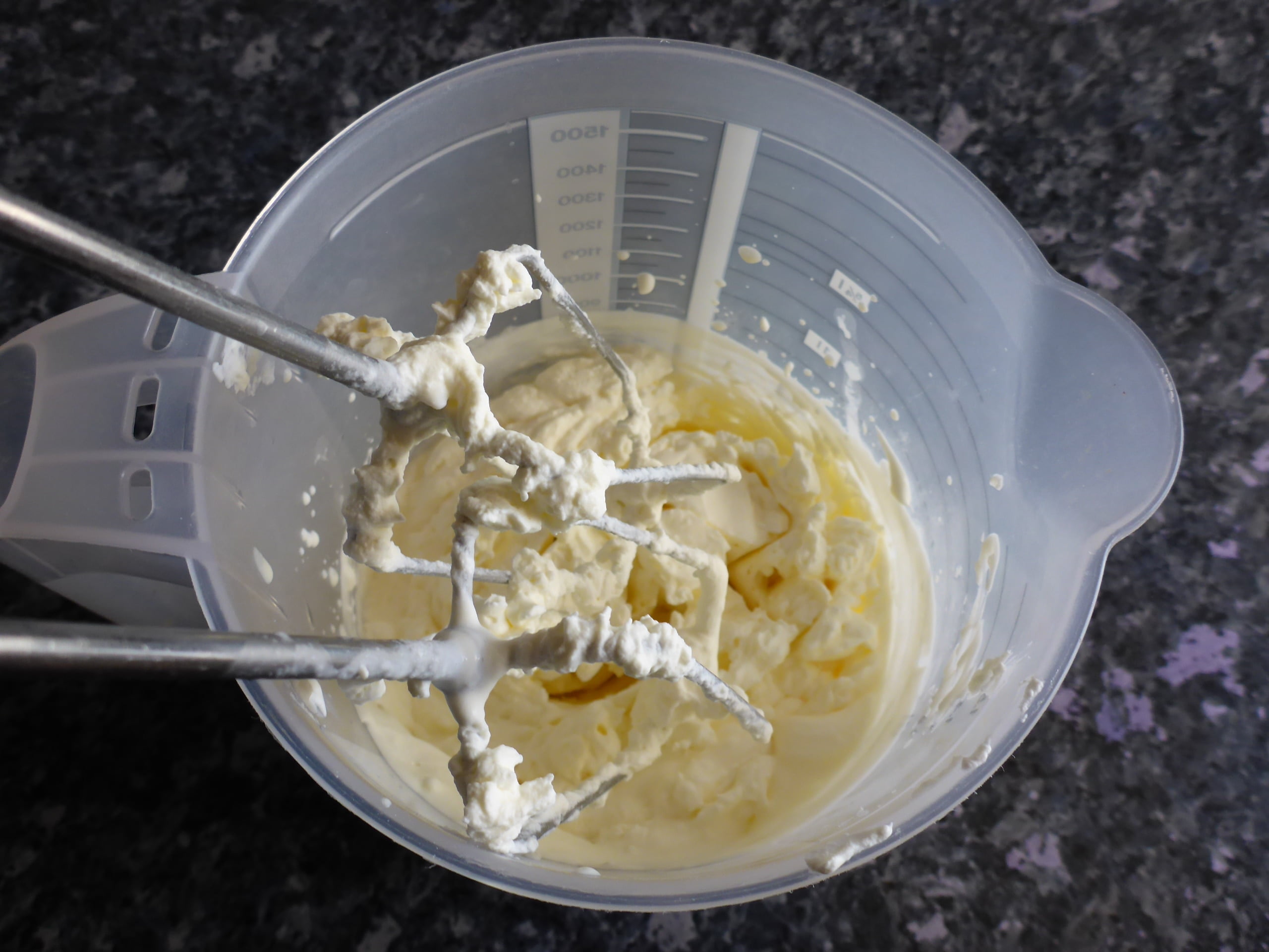 Schritt-für-Schritt-Anleitung für die Zubereitung von Vanilleeis ohne Eier: Die Schlagsahne wird steif geschlagen, um Volumen und eine cremige Textur zu erzeugen.