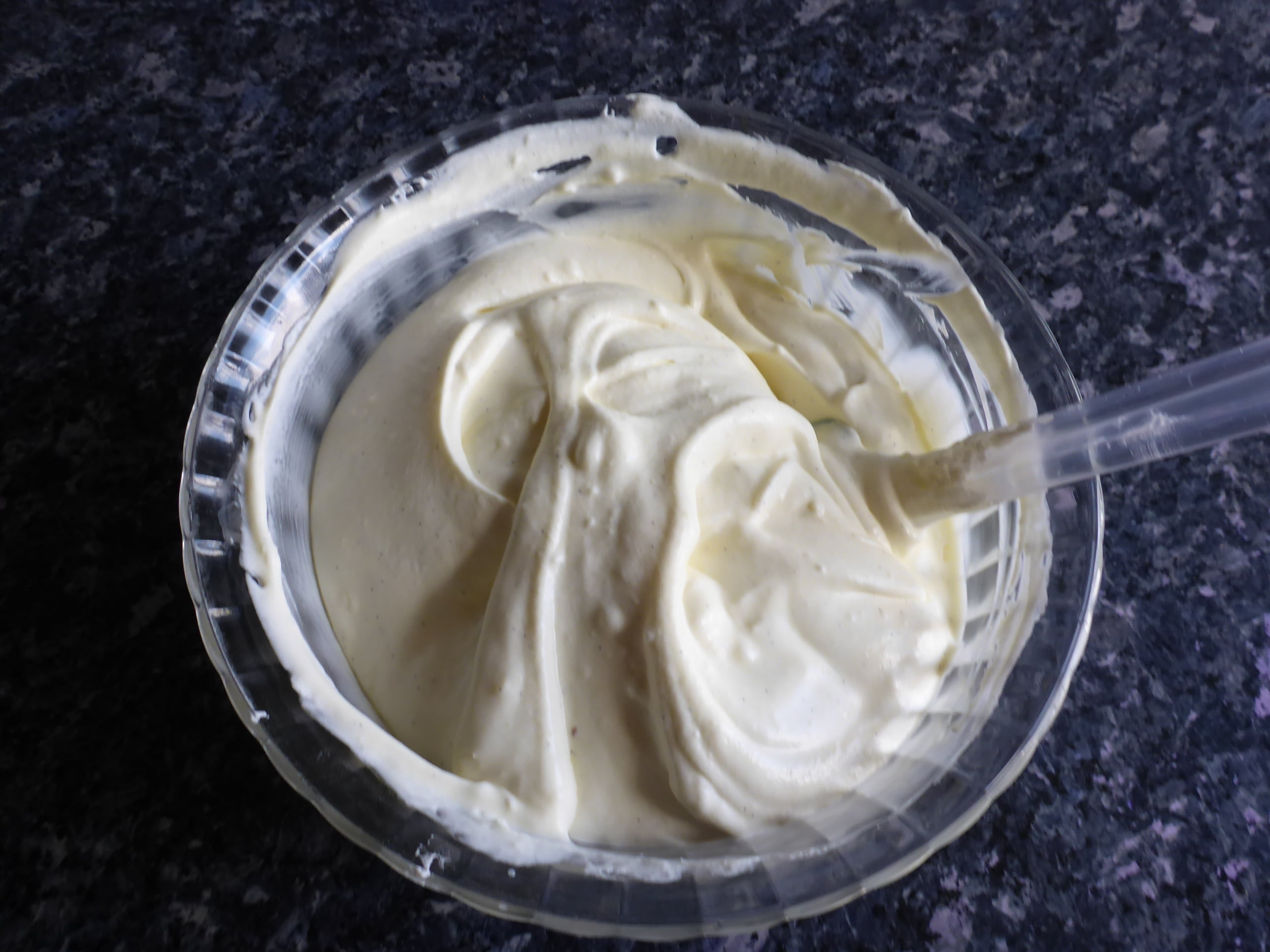 Schritt-für-Schritt-Anleitung für die Zubereitung von Vanilleeis ohne Eier: Die geschlagene Sahne wird sanft unter die Kondensmilchmischung gehoben, bis alles gut vermischt ist.
