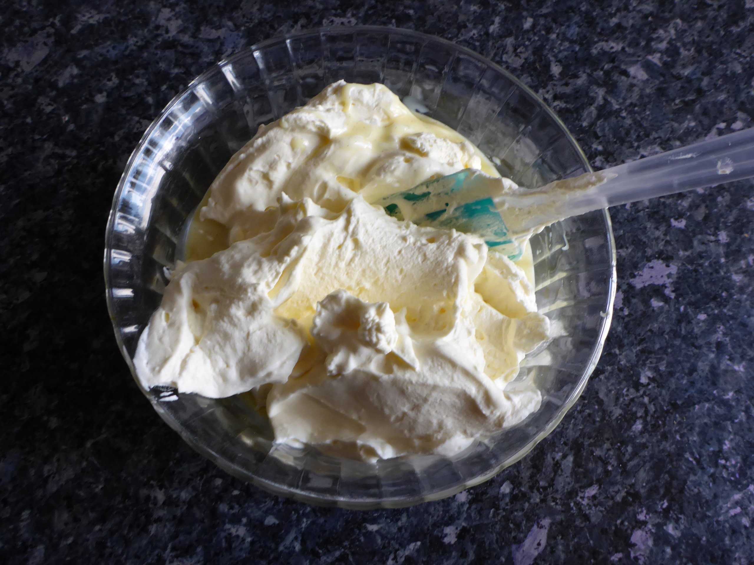 Schritt-für-Schritt-Anleitung für die Zubereitung von Vanilleeis ohne Eier: Die geschlagene Sahne wird sanft unter die Kondensmilchmischung gehoben, bis alles gut vermischt ist.