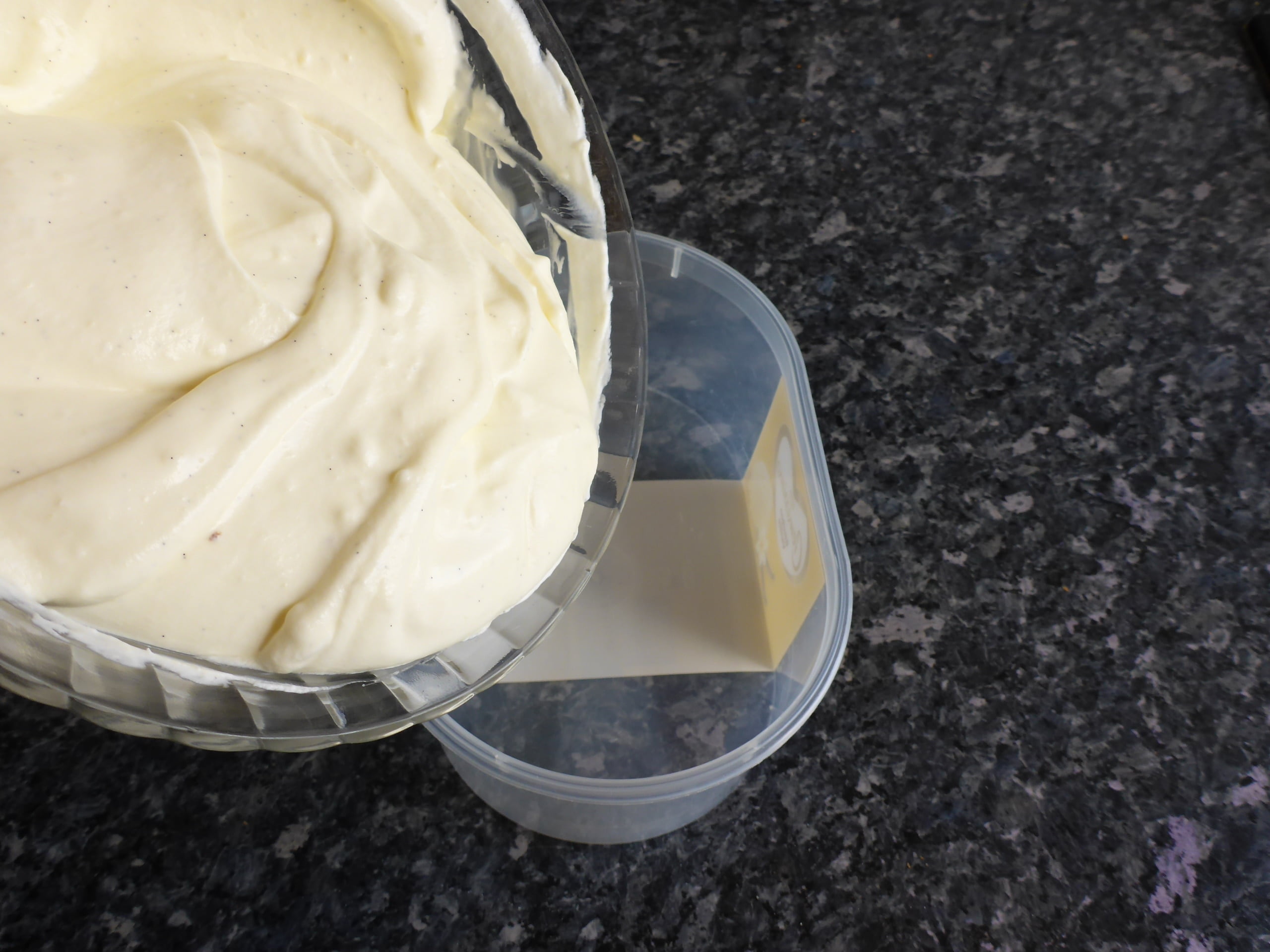 Schritt-für-Schritt-Anleitung für die Zubereitung von Vanilleeis ohne Eier: Die entstandene Eismischung wird in einen Behälter gefüllt und für mehrere Stunden ins Gefrierfach gestellt, bis sie fest wird.