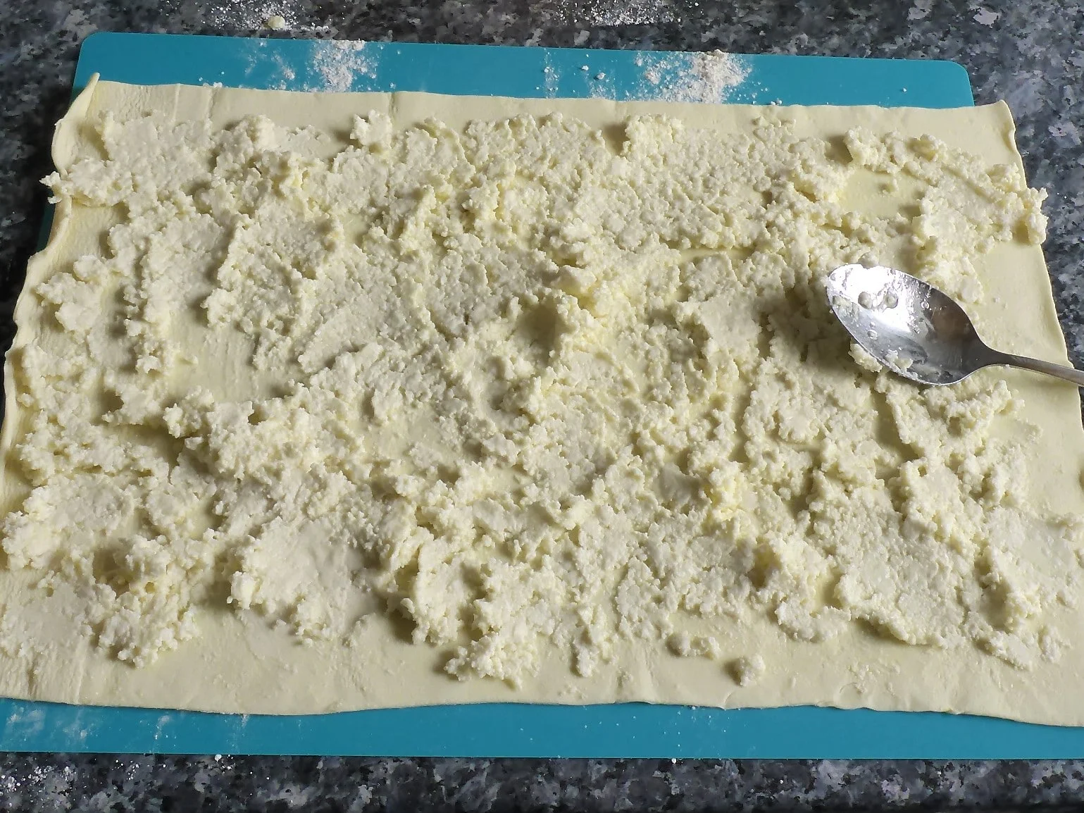Blätterteigschnecke vegetarisch Zubereitungsschritte: Auf dem Bild ist Blätterteig bestrichen mit Feta - Olivenölcreme zu sehen.
