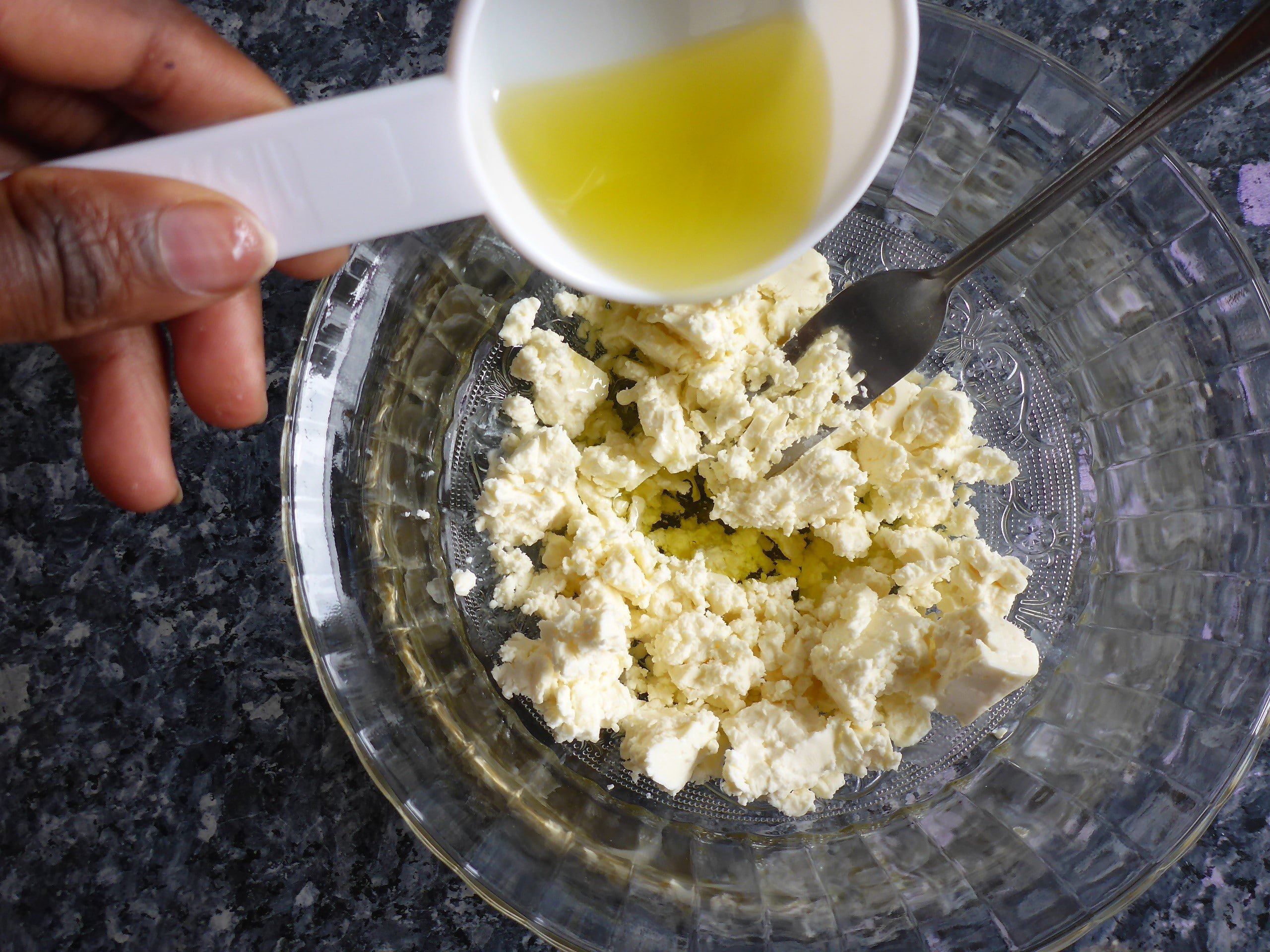 Blätterteigschnecke vegetarisch Zubereitungsschritte: Auf dem Bild ist zerdrückte Feta in einer Schüssel und Olivenöl wird hinzugefügt zu sehen.