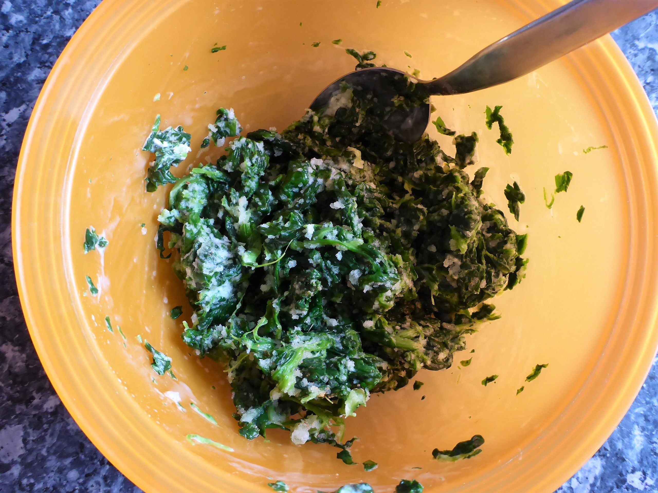 Blätterteigschnecke vegetarisch Zubereitungsschritte: Auf dem Bild ist Aufgetaut Spinat in einer Schüssel gemischt mit Frischkäse zu sehen.