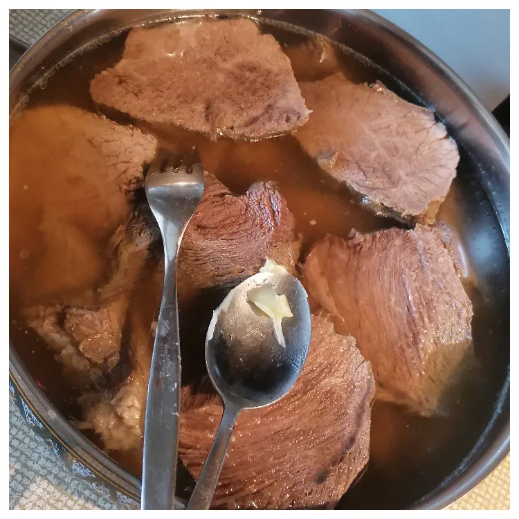 Cooked sour German braised beef cut in broth cut into slices.