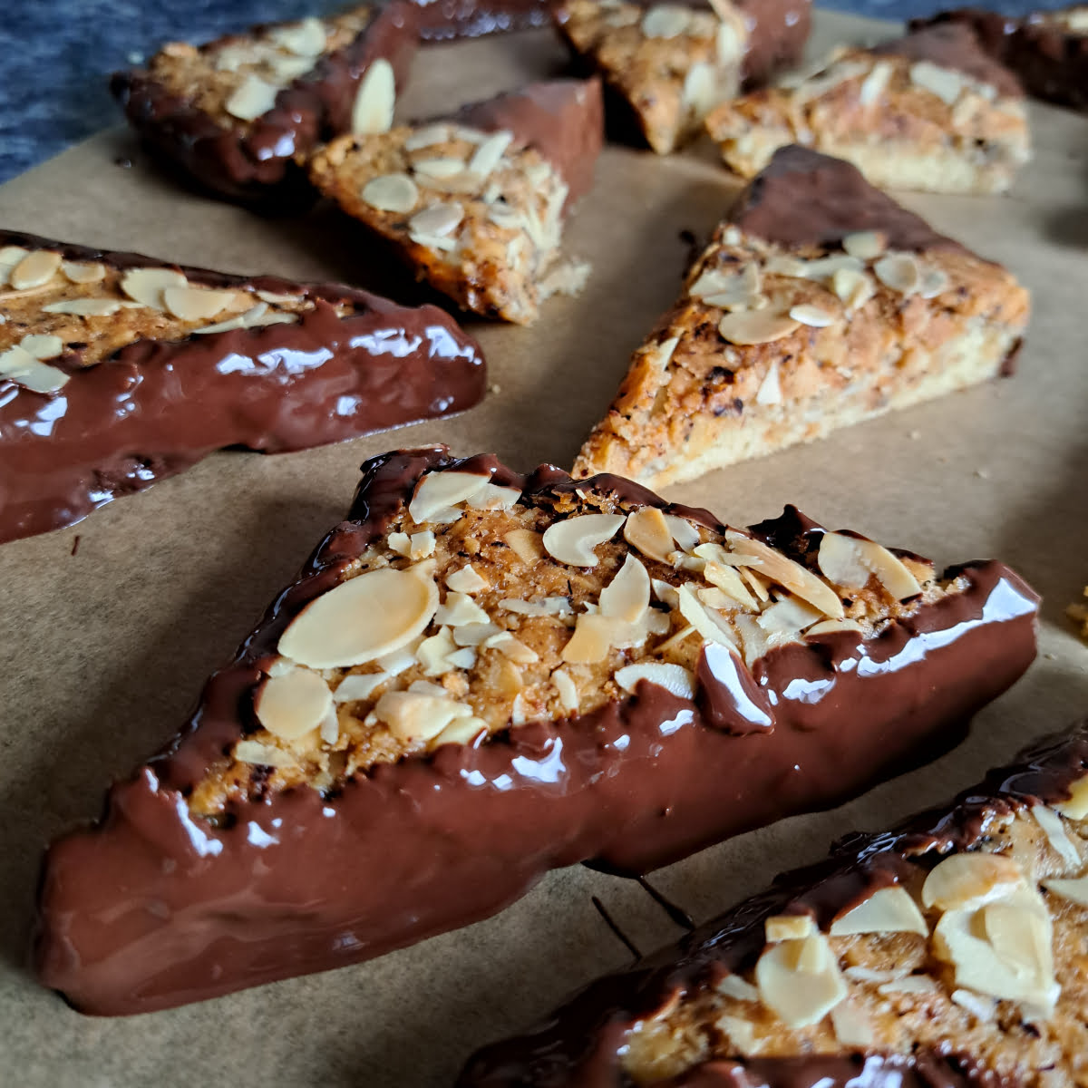 German nut corners that are freshly dipped in melted chocolate placed on a parchment paper to dry.