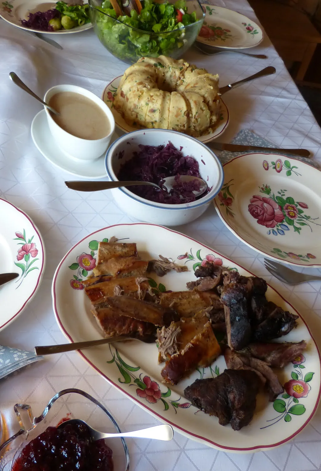 Ein schöner gedeckter Tisch, drauf zusehen ist Rehbraten, Blaukraut, Rosenkohl, Preiselbeeren, Semmelknödel und Grünensalat, 