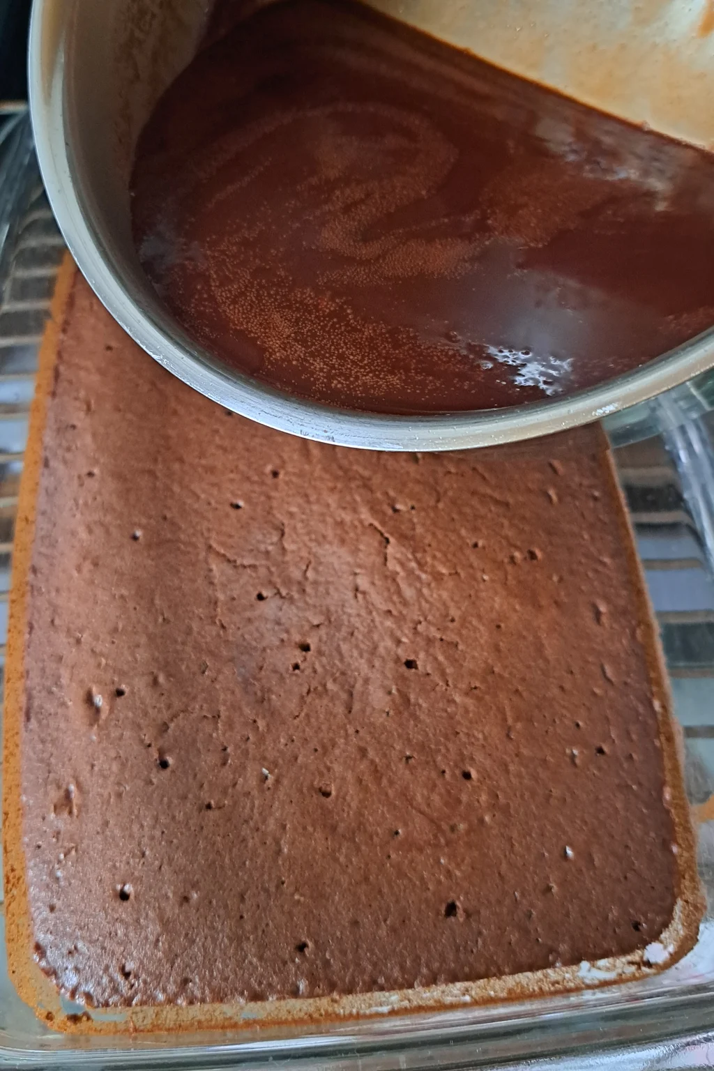 While the cake is still hot, poke holes on the surface of the pudding and pour chocolate Sauce