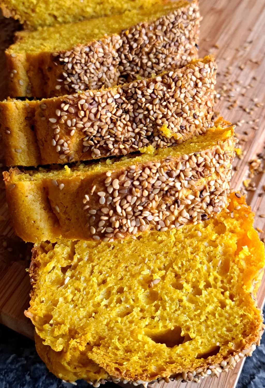 Freshly baked South African corn bread (also known as mielie bread) on a wooden cutting board sprinkled with sesame seeds.