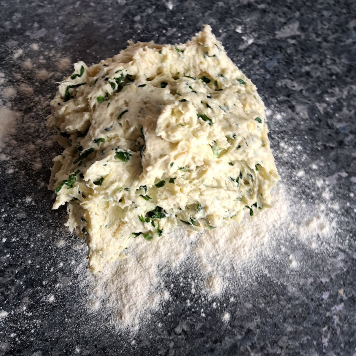 Freshly made wild garlic dough getting kneaded on a kitchen counter.