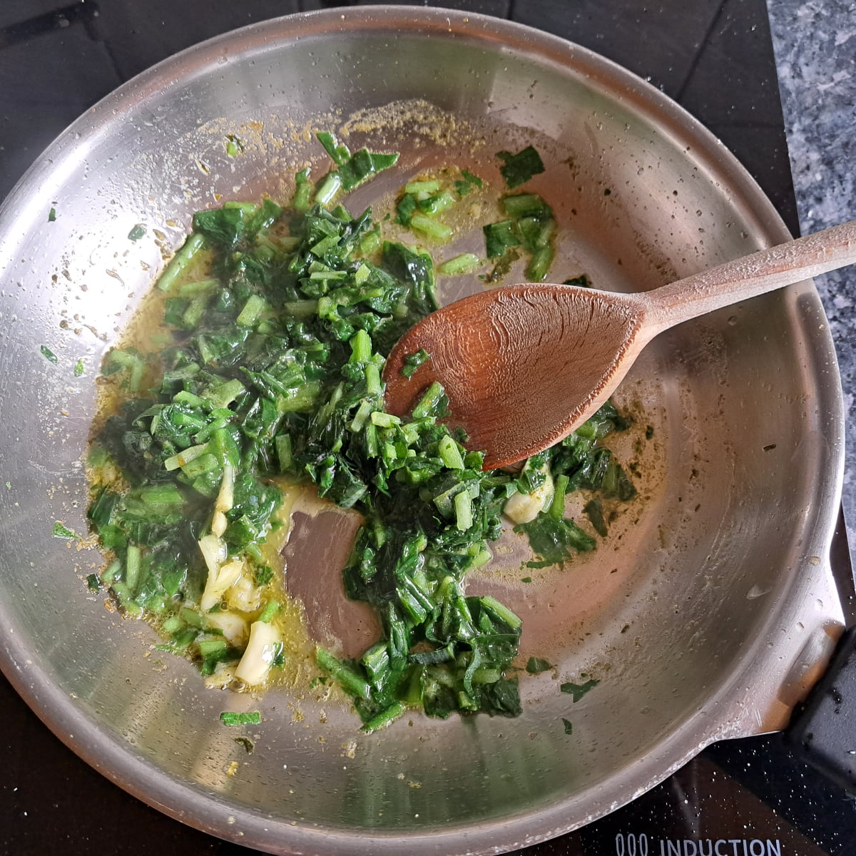 Die Herstellung von Bärlauchsoße. Bärlauch in Butter und Olivenöl kurz anbraten.