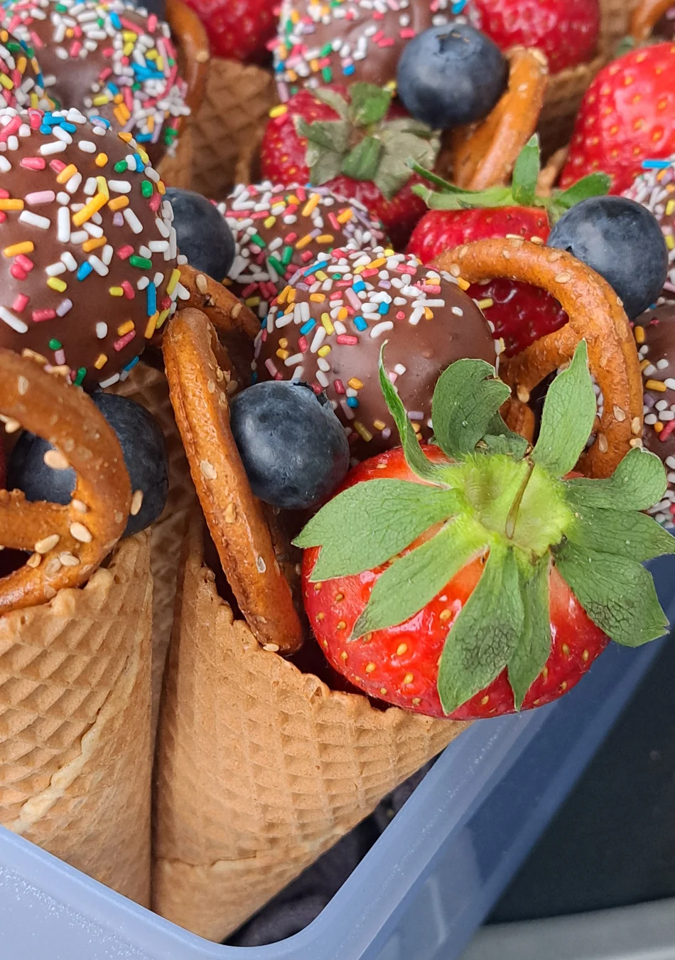 Kunterbunte-Eistüte-ist-gefüllt-mit-frischem-Obst-und Kuchen am Stiel (Cake pops).
