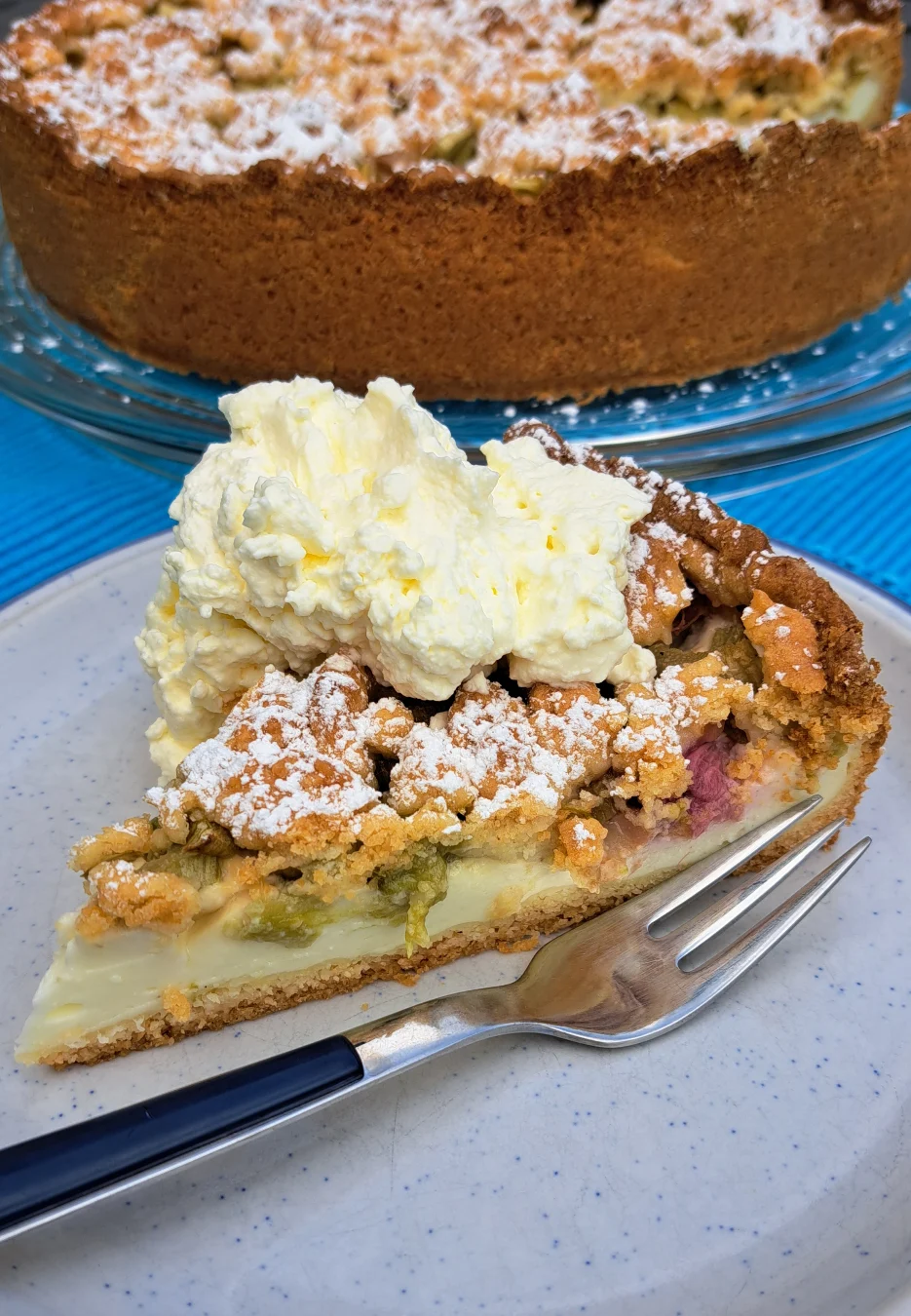 Ein frisch gebackener Rhabarberkuchen mit Streusel bestäubt mit Puderzucker.