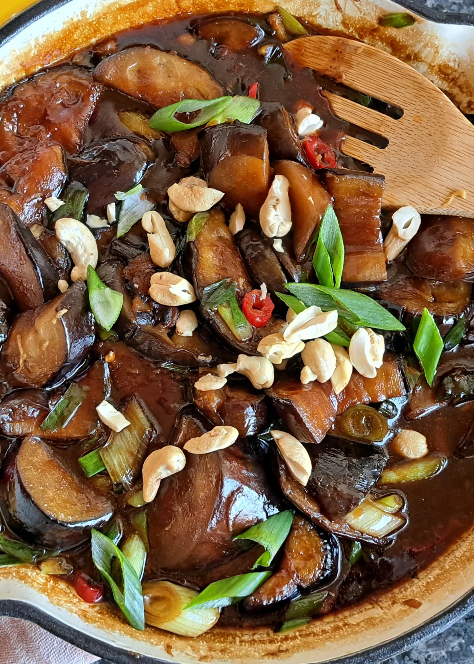 Asiatische Aubergine in süß-sauer Sauce garniert mit Frühlingszwiebeln und Nüssen.