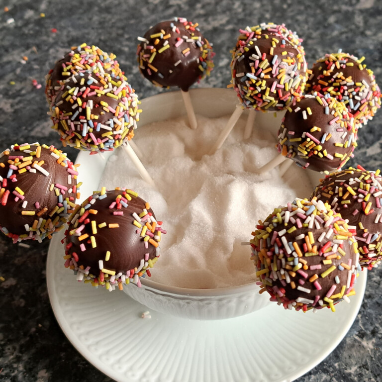 Köstliche Kuchen am Stiele, die in einer Schüssel mit Zucker zum Abtrocknen platziert sind.
