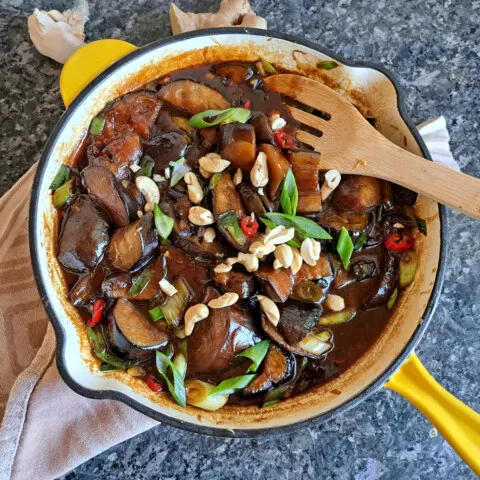 Asiatische Aubergine in süß-sauer Sauce garniert mit Frühlingszwiebeln und Nüssen.