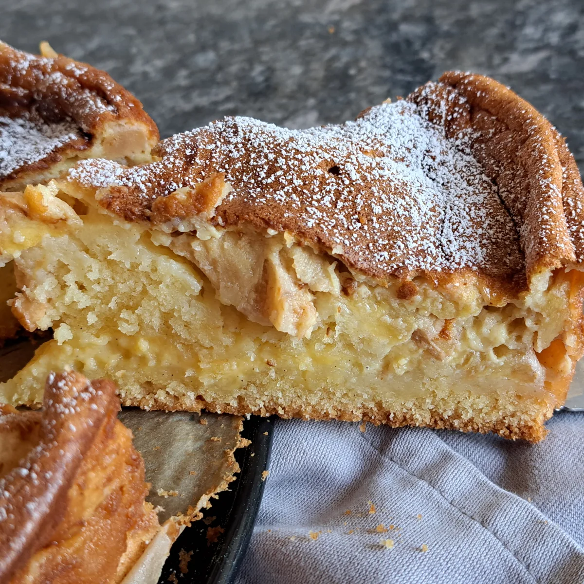 Ein köstlicher Apfel Pudding Kuchen, frisch aus dem Ofen, mit einer goldbraunen Kruste und saftigen Apfelstücken.