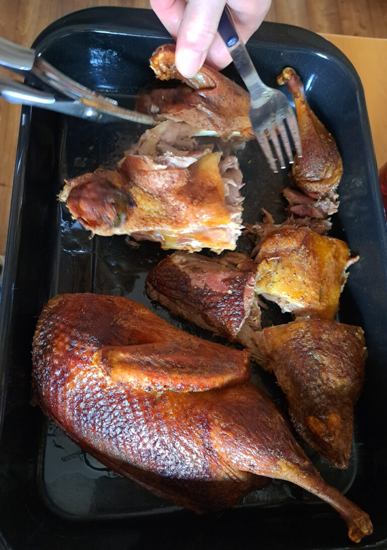 Fertig gebackene, knusprige Ente ohne Füllung auf einem Backblech.