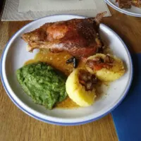 Ein Bild zeigt einen schön angerichteten Teller mit Ente im Backofen ohne Füllung, einer klaren Sauce aus dem ausgetretenen Fett, Kartoffelklößen und fränkischem Wirsing.