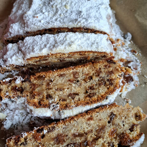 Ein saftiger Quarkstollen, großzügig mit Puderzucker bestäubt und in verlockende Scheiben geschnitten.