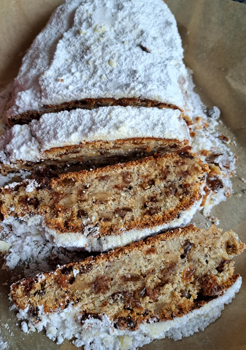 Ein saftiger Quarkstollen, großzügig mit Puderzucker bestäubt und in verlockende Scheiben geschnitten.