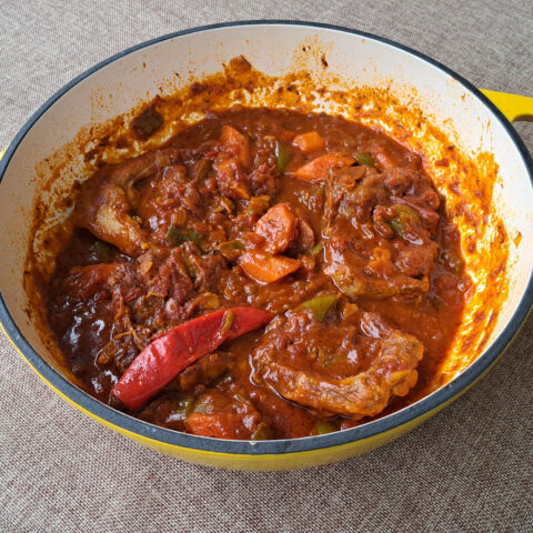 Image of a yellow cast iron pot of lamb potjie containing fall-apart tender lamb immersed in an incredibly rich and deep-flavored sauce.