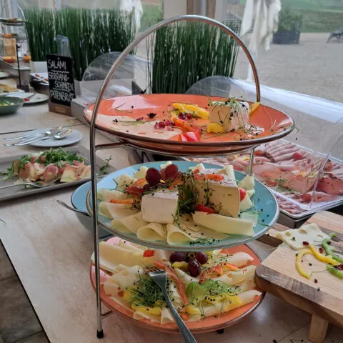 Bild einer ansprechend präsentierten Wurst- und Käseplatte im Café Schloss Seehof, teilweise auf einer dreistufigen Etagere angerichtet.