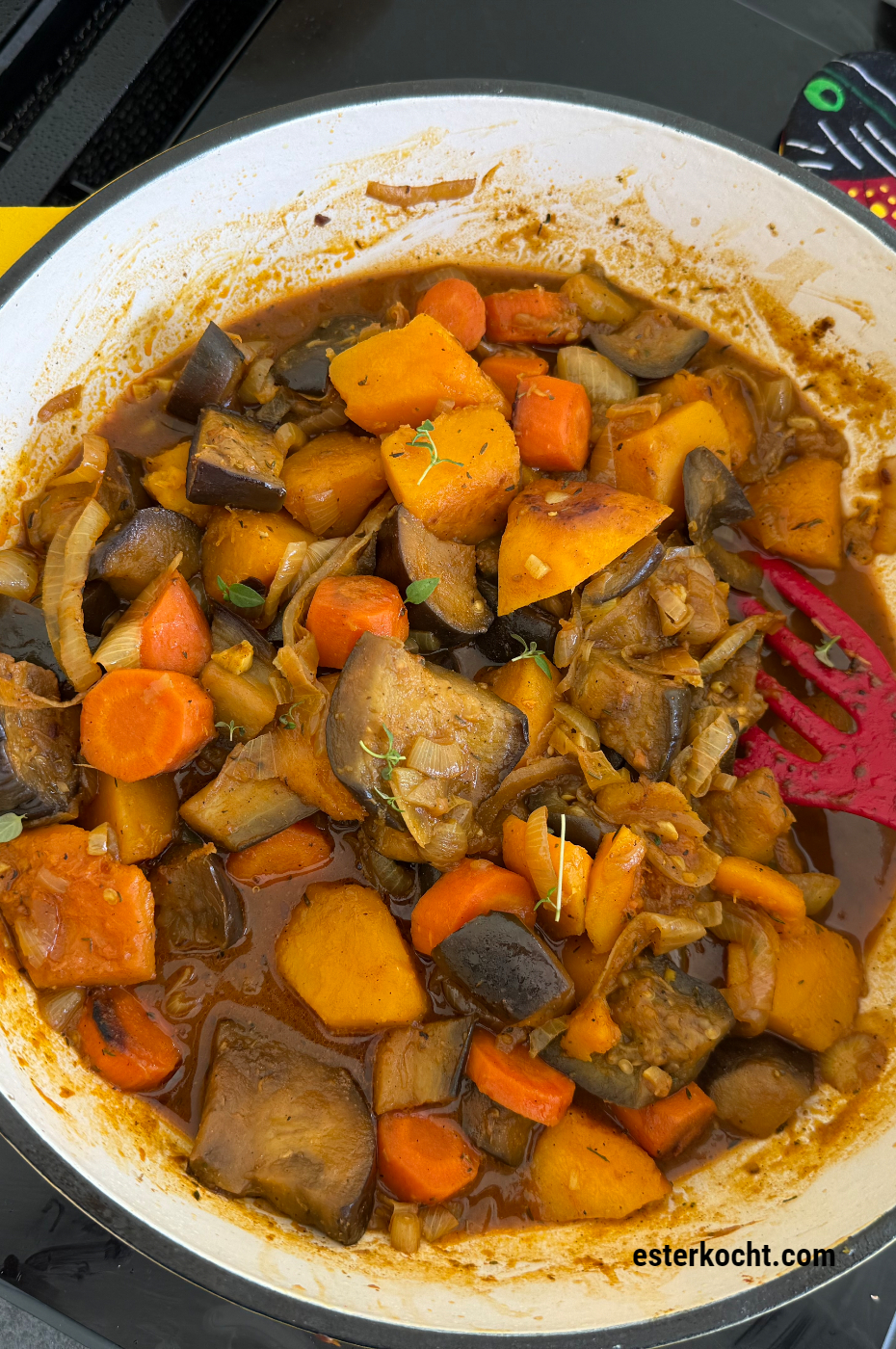 Frisch gekochter afrikanischer vegetarischer Eintopf aus Butternut-Kürbis, Auberginen und Zwiebeln in einem Schmortopf garniert mit frischem Thymian.
