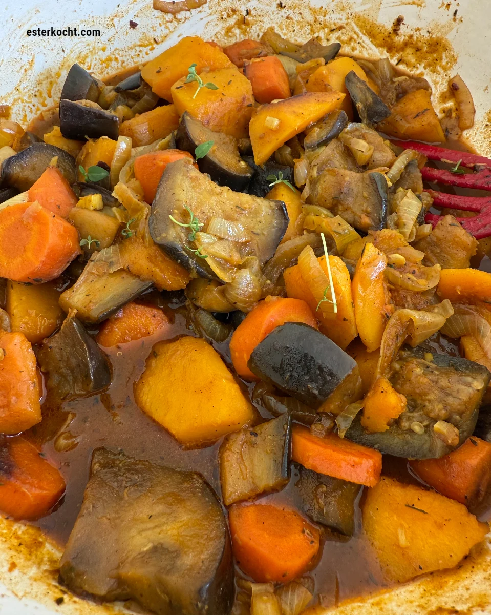 Frisch gekochter afrikanischer vegetarischer Eintopf aus Butternut-Kürbis, Auberginen und Zwiebeln in einem Schmortopf garniert mit frischem Thymian.