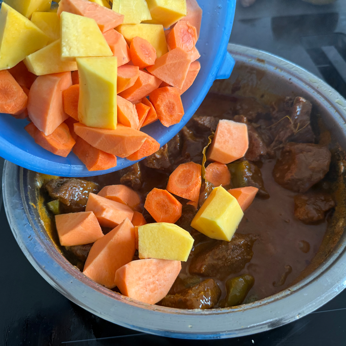 Butternutkürbis, Süßkartoffeln und Karotten werden geschält, gewürfelt und zusammen mit heißem Wasser in den Schmortopf gegeben – Schritt für namibisches geschmortes Rindfleisch.