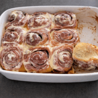 Frisch gebackene, superweiche und saftige Zimtschnecken mit Frischkäse-Topping in einer Auflaufform, zubereitet mit Mehlkochstück nach der Tangzhong-Methode.