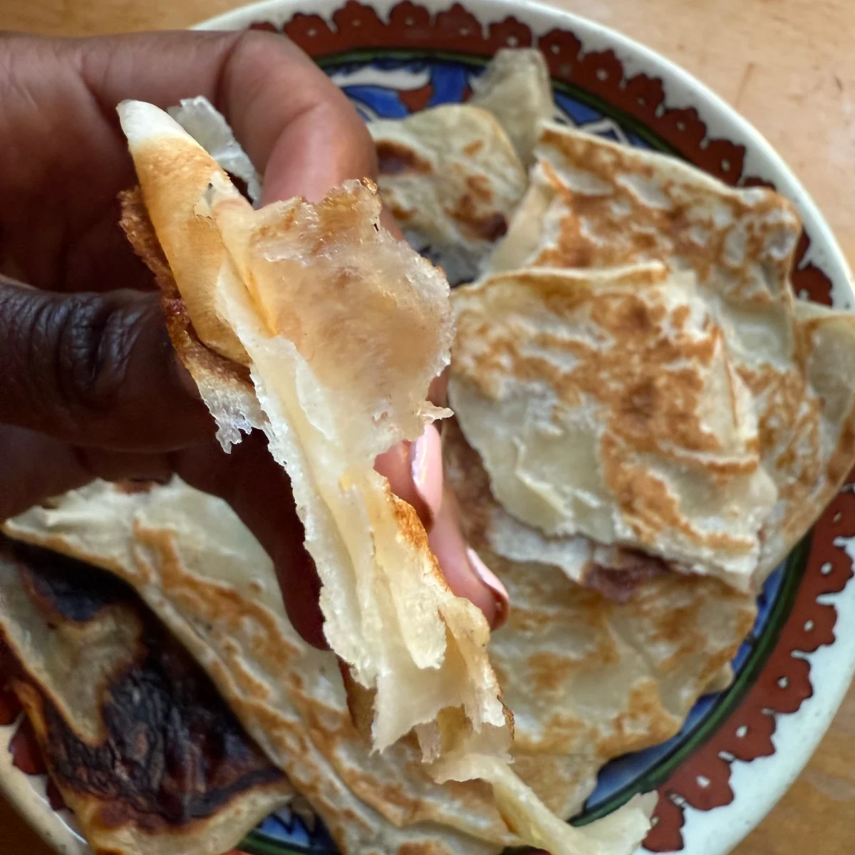 Freshly baked Somali flatbread torn apart, showing soft and flaky layers.