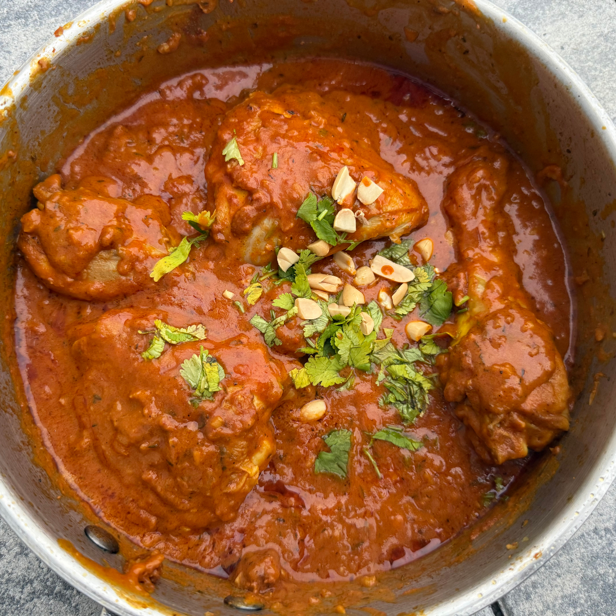 frisch gekochter afrikanischer H&auml;hnchen-Erdnusseintopf getoppt mit Erdn&uuml;sse und frischem Koriander