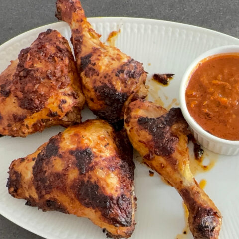 Servierfertiges afrikanisches Ofenh&auml;hnchen auf einer Platte mit So&szlig;e