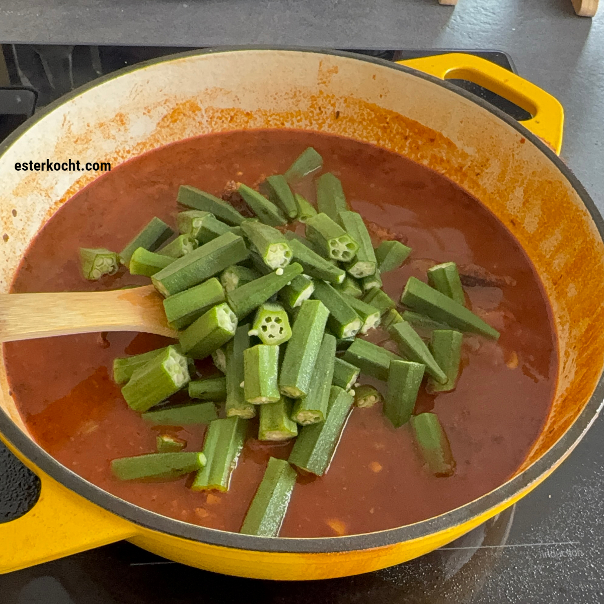 Frisch geschnittene Okraschoten werden in den Topf gegeben, um das afrikanische Okra Rezept fertig zu kochen