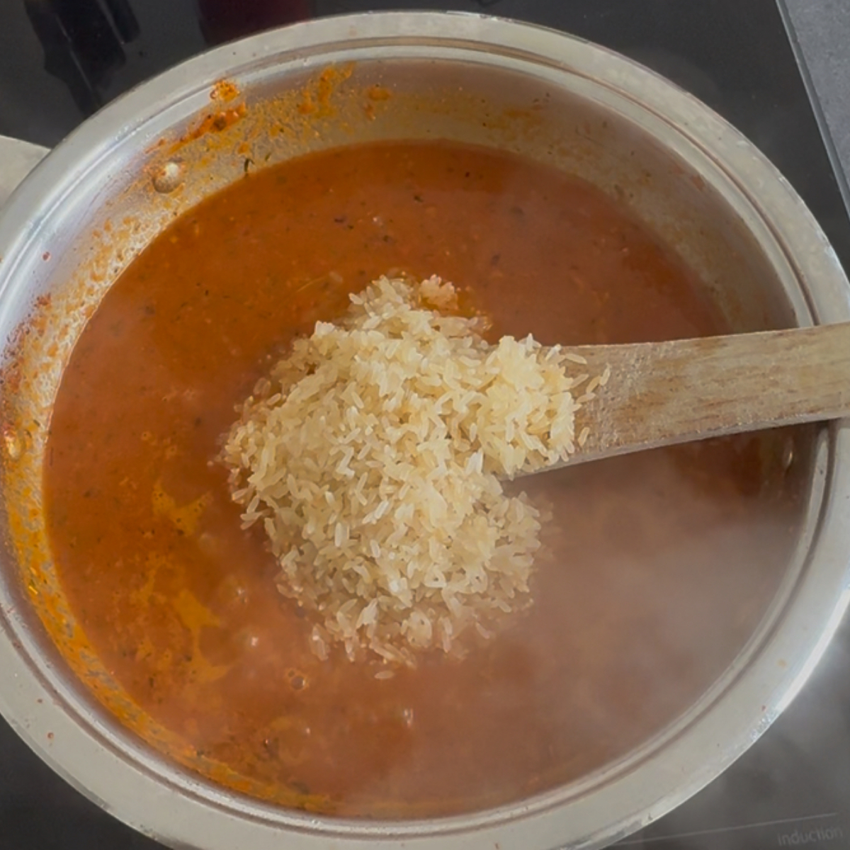 Reis wird in würziger Tomaten-Paprika-Sauce gekocht für ein klassisches Jollof Reis Rezept