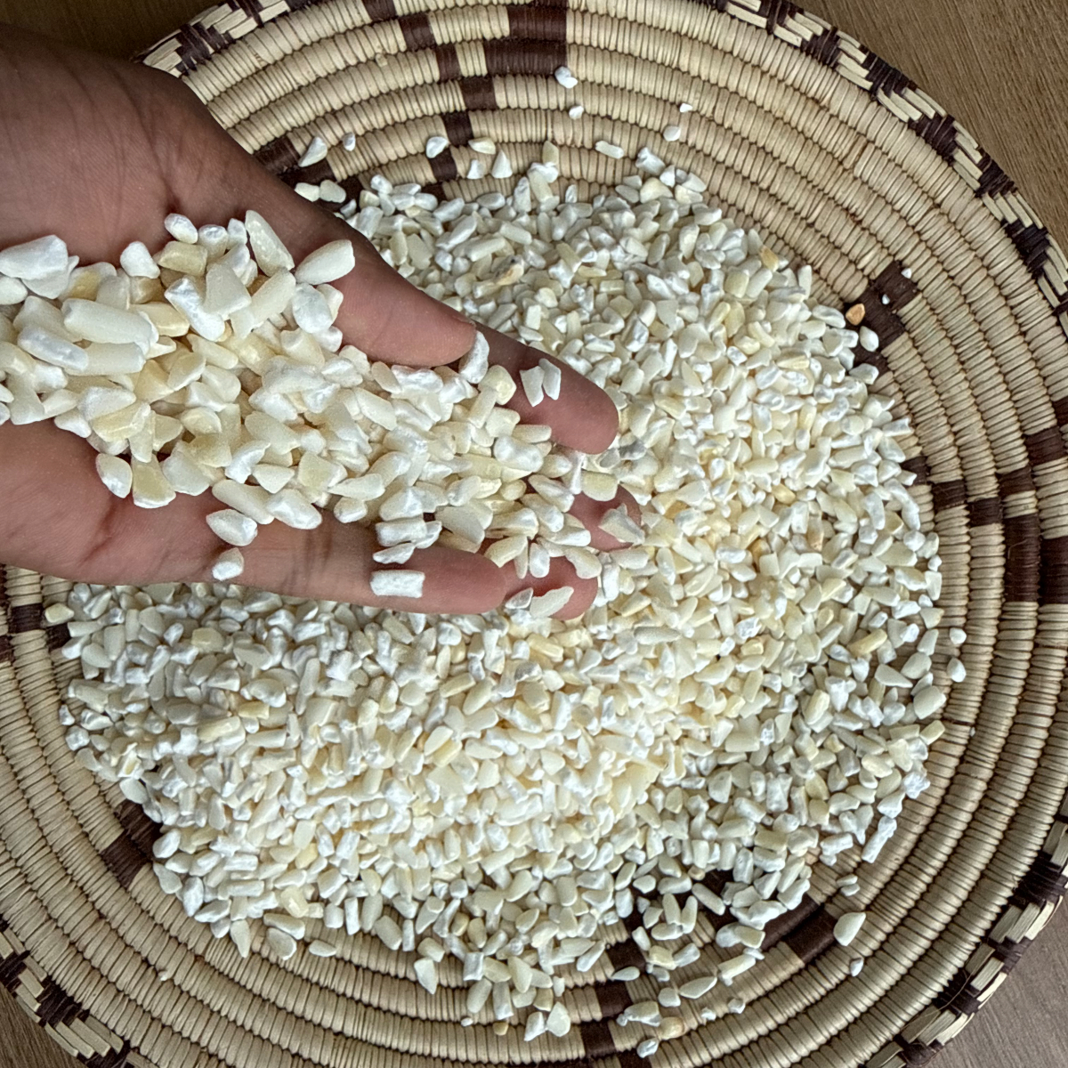 Dried samp (cracked maize kernels) displayed in a traditional handwoven basket from Namibia.