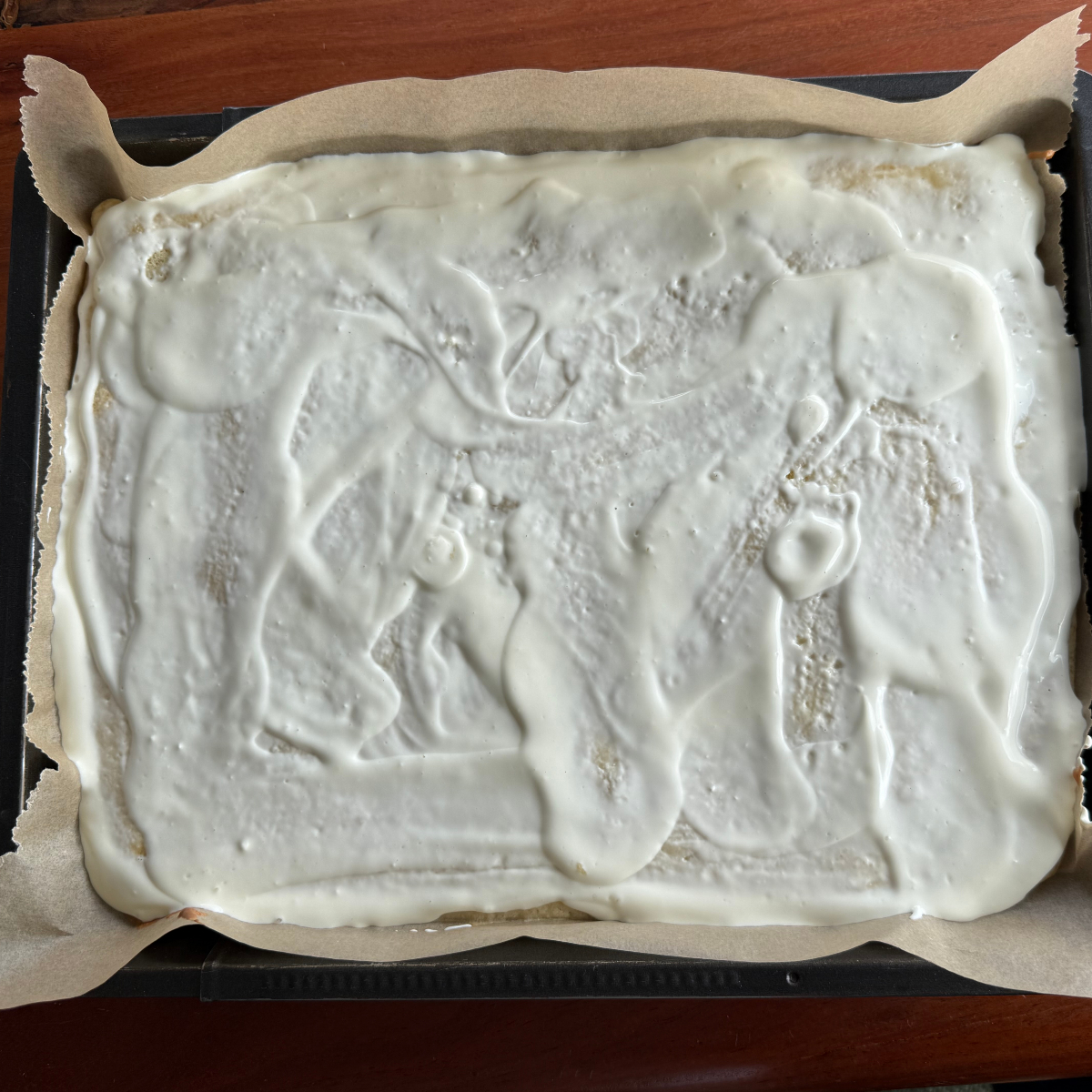 Vorgebackener Rührteig mit einer Schicht Schmand bestrichen.