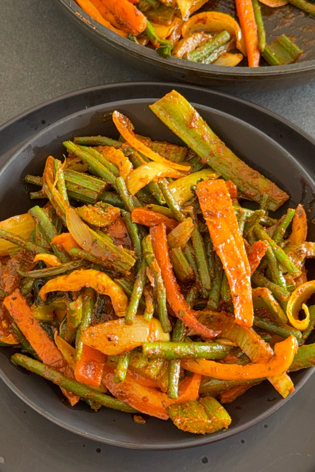 Bunte vegane Gemüsepfanne mit grünen Bohnen, Stangensellerie, Karotten und Paprika auf einem tiefen Teller
